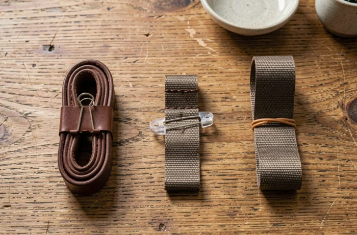 Trois astuces pour faire tenir une ceinture sans percer de trou présentées en flat lay sur une table en bois