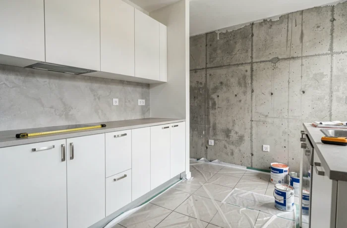 Cuisine en cours de rénovation avec nouveaux placards installés et mur en béton brut visible, illustrant les travaux de rénovation intérieure